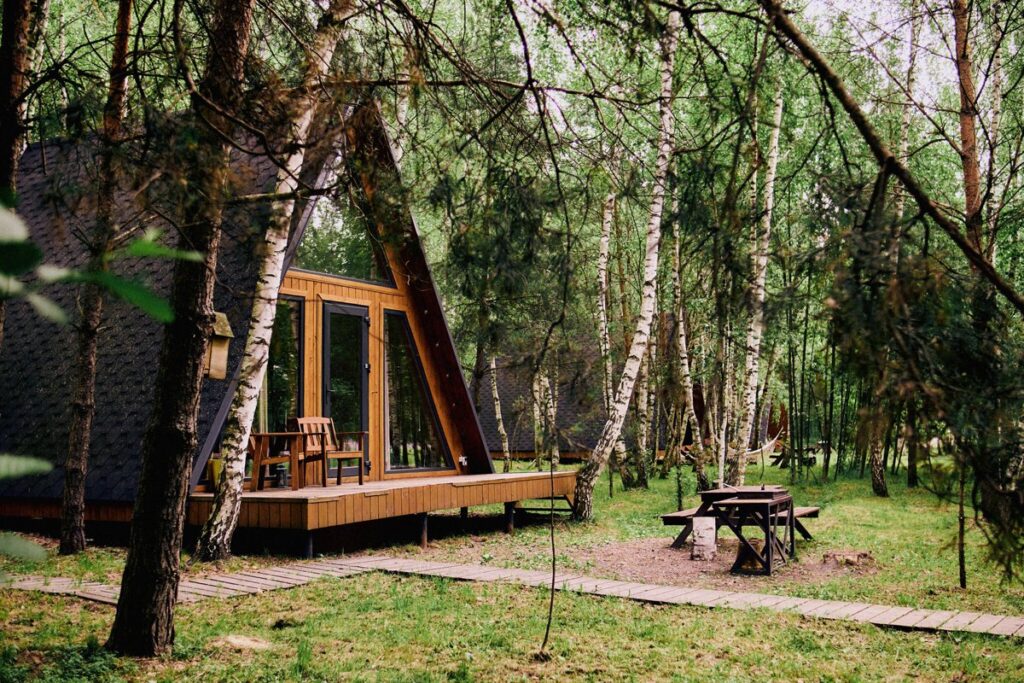 Маленький A-frame дом 36 м² с подвесным креслом, шесть одинаковых: дом с террасой в соснах