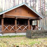 База отдыха Рыбачий Берег на озере Отрадное, общий вид: бревенчатый дом в соснах