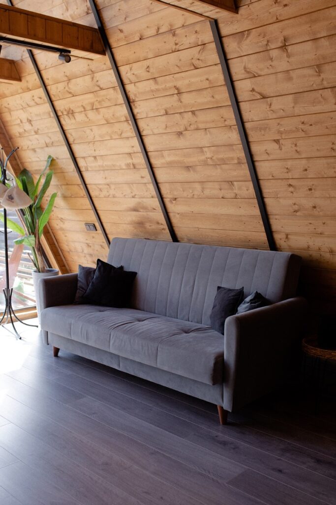 Дом A-Frame «Серый» с баней, чаном и бассейном до 6 гостей: диван в гостиной
