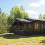 Загородный клуб Заповедное в Ильинке, общий вид: дом-сруб на лужайке