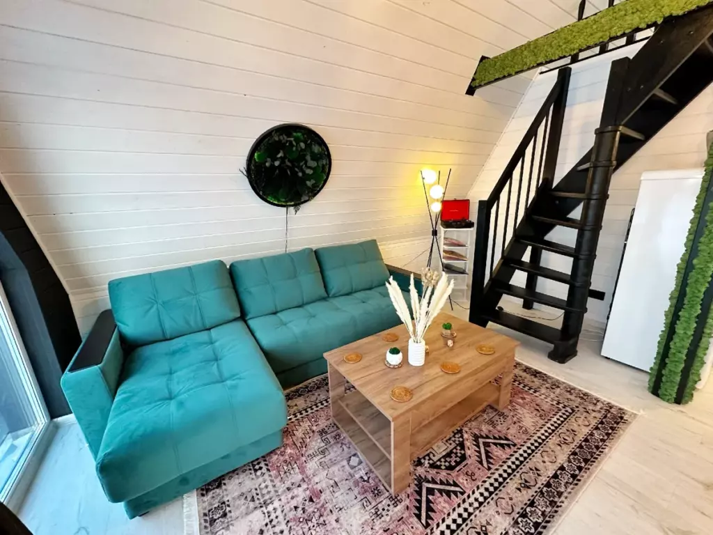 Дом Luxe A-frame 65 м² с камином и двумя спальнями до 6 гостей: гостиная с бирюзовым диваном
