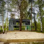 Загородный клуб Восемь обезьян у реки Киржач, общий вид: дом за песчаной площадкой